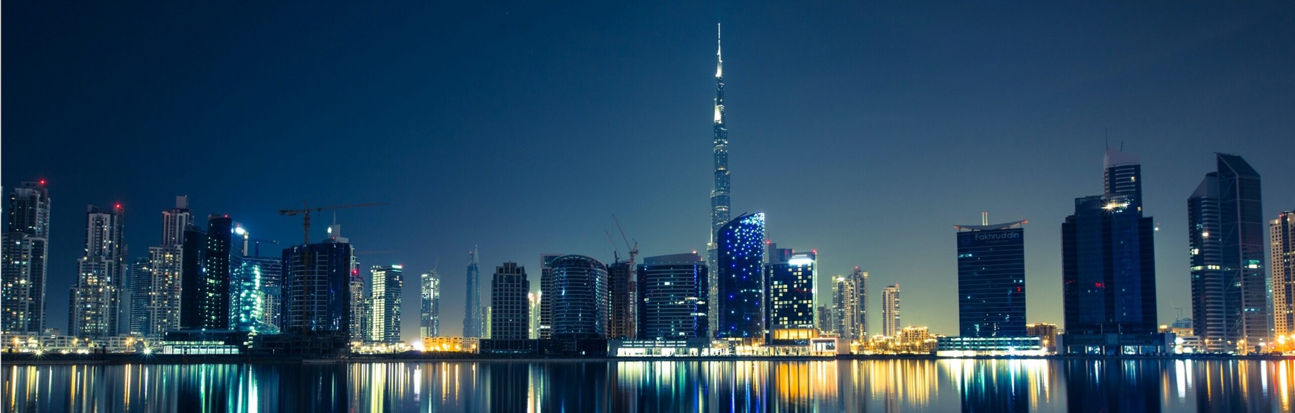 Dubai skyline at night, with reflections of buildings and lights in water