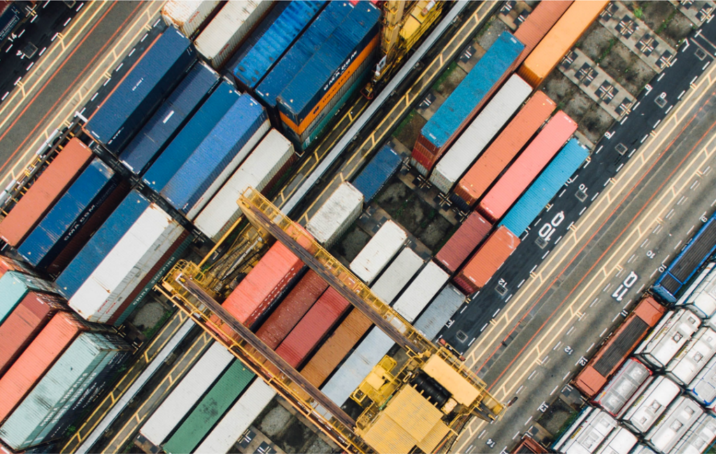 An aerial view of shipping containers at a port-side, making colourful diagonal lines. Private Networks: mix-and-match model + bespoke optimisations