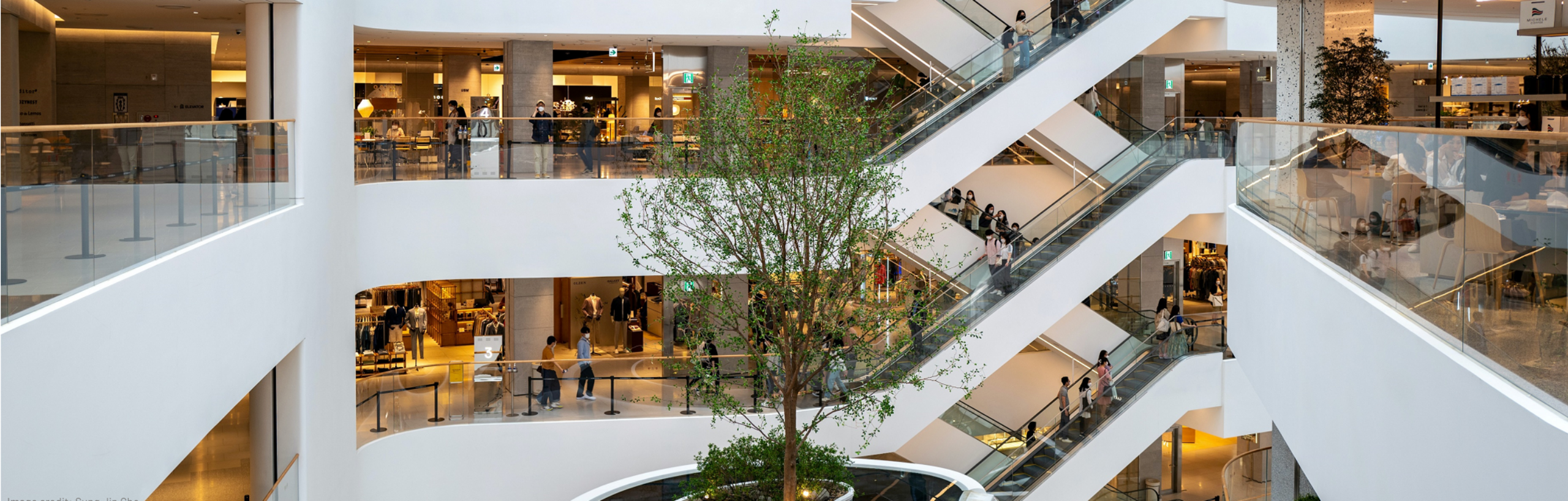 A white multi-level shoppping centre, with a tree in the centre - In-building coverage testing without an engineer on-site